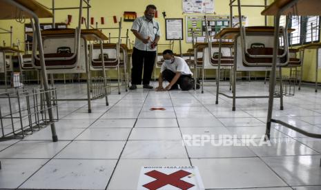 Petugas memasang tanda jarak fisik (physical distancing) di ruang kelas di SMAN 5 Bandung, Jalan Belitung, Kota Bandung, Senin (8/6). Sekolah tersebut mulai melakukan persiapan protokol kesehatan jelang tahun ajaran baru seperti pembatasan jumlah siswa di ruang kelas, penerapan jarak duduk, fasilitas cuci tangan di setiap kelas serta pengaturan jam masuk sekolah siswa dalam masa Pembatasan Sosial Berskala Besar (PSBB) secara proporsional menuju adaptasi kebiasaan baru (AKB) saat pandemi Covid-19