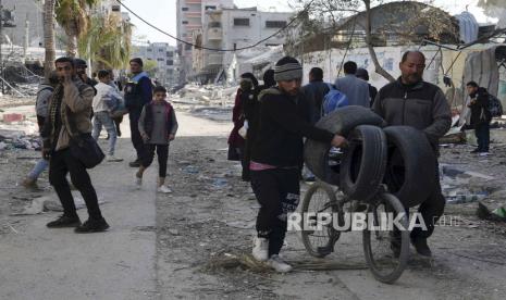 Warga Palestina berjalan melalui kehancuran akibat pemboman Israel di kamp pengungsi Nusseirat di Jalur Gaza, Selasa, (16/1/2024).