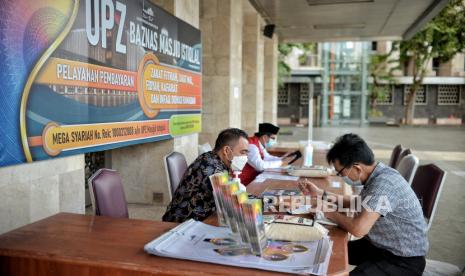 Warga membayar zakat fitrah di Unit Pengumpul Zakat (UPZ) Badan Amil Zakat Nasional (Baznas) Masjid Istiqlal, Jakarta, Selasa (4/5).  Baznas Masjid Istiqlal membuka layanan zakat fitrah untuk masyarakat umum hingga malam takbir dengan besaran 3,5 liter atau 2,7 kilogram beras atau uang sebesar Rp 50.000 per orang. Republika/Thoudy Badai