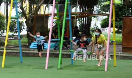 Seorang perempuan dan anak-anak menggunakan masker saat bermain ayunan di Taman Catur, Pontianak, Kalimantan Barat. Pastikan anak selalu mematuhi anjuran 5 M saat keluar rumah.