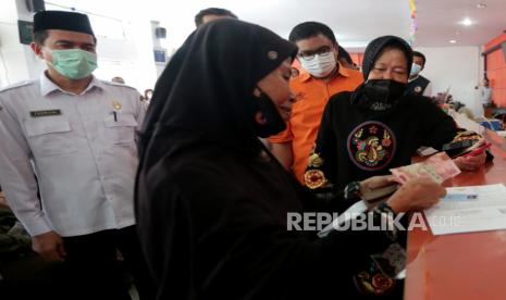 Menteri Sosial Tri Rismaharini (kanan) melihat warga penerima bantuan langsung tunai (BLT) pengalihan subsidi bahan bakar minyak (BBM) menghitung uang yang diterimanya di kantor PT Pos Indonesia, Banda Aceh, Aceh, Rabu (14/9/2022). Kementerian Sosial menyalurkan BLT pengalihan subsidi BBM kepada 20,65 juta keluarga penerima manfaat (KPM) senilai Rp12,4 triliun melalui PT Pos Indonesia. 