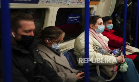 Komuter di kereta bawah tanah London memakai masker wajah untuk mengekang penyebaran COVID-19, sekarang wajib di angkutan umum di Inggris setelah munculnya varian Omicron baru, di London, Selasa, 30 November 2021. Menkes Inggris laporkan Omicron menyebar sangat cepat dan bisa membanjiri rumah sakit.