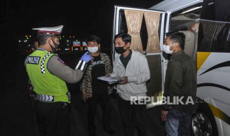 Polisi memeriksa surat tiga orang TKI (Tenaga Kerja Indonesia) dari luar negeri di tol Jakarta-Cikampek, Cikarang, Kabupaten Bekasi, Jawa Barat, Sabtu (25/4/2020). Pada hari kedua penyekatan pemudik di jalan tol masih banyak kendaraan yang tidak mengatur jarak sosial  dan warga yang memaksaan untuk mudik