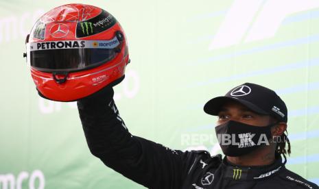  Pemenang Formula Satu Inggris Lewis Hamilton dari Mercedes-AMG Petronas (kiri) merayakan memegang helm legenda F1 Michael Schumacher, yang diserahkan kepadanya oleh putra Michael, Mick Schumacher, setelah Grand Prix Formula Satu Eifel 2020 di trek balap Nuerburgring di Nuerburg, Jerman, 11 Oktober 2020. 