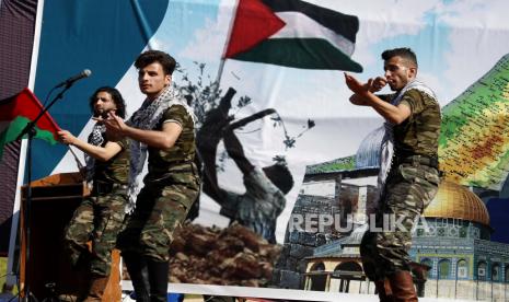 Pria yang mengenakan seragam militer menampilkan Dabke, tarian rakyat Levantine yang terlihat pada acara-acara gembira selama rapat umum yang menandai peringatan 46 tahun Hari Tanah, di dekat pagar perbatasan Jalur Gaza dengan Israel, sebelah timur Kota Gaza, Sabtu, 26 Maret 2022. Israel Ketakutan, Tutup Penyeberangan Gaza tanpa Batas Waktu