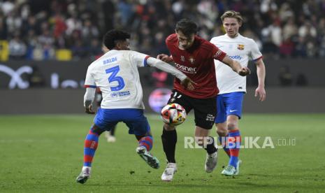 Alejandro Balde dari Barcelona (kiri) berebut bola dengan Ante Budimir dari Osasuna (tengah) saat pertandingan sepak bola semifinal Piala Super Spanyol antara Osasuna dan Barcelona di Stadion Al Awal Park di Riyadh, Arab Saudi, Jumat (12/1/2024) dini hari WIB. 