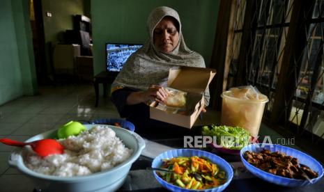 Hadjiah (54 tahun) pemilik UMKM Dapoer Mpok Iyah mengemas nasi box pesanan di rumahnya di kawasan Cakung, Jakarta Timur, Selasa (20/2/2024). UMKM Dapoer Mpok Iyah merupakan UMKM binaan PT Jakarta Industrial Estate Pulogadung (PT JIEP) yang menjual beragam jenis makanan seperti camilan stik bawang, nasi kebuli hingga melayani jasa catering bersertifikasi halal dari MUI. 