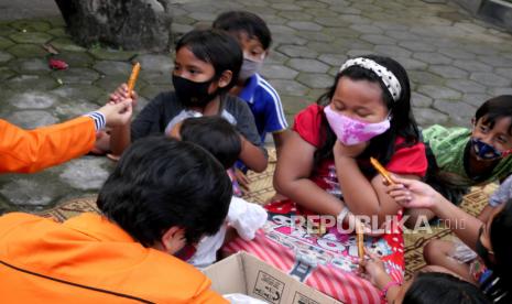 Anak-anak bermain sambil belajar bersama sambil memakai masker.