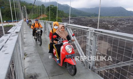 Warga bersepeda motor melintasi jembatan gantung. (Ilustrasi)