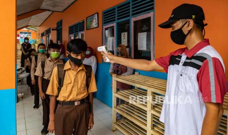 Kelonggaran Belajar Tatap Muka Kurangi Stres Akibat PJJ. Seorang guru memeriksa suhu tubuh siswa yang akan mengikuti kegiatan belajar mengajar (KBM) tatap muka di SMP N 6 Lerep Satu Atap, Kecamatan Ungaran Barat, Kabupaten Semarang, Jawa Tengah, Jumat (27/11/2020). Sejumlah sekolahan di wilayah Kabupaten Semarang telah mempersiapkan KBM tatap muka dengan menerapkan protokol kesehatan COVID-19 dan meminta persetujuan orang tua siswa pada penyelenggaraan semester genap tahun ajaran 2020-2021 yang akan dimulai pada 2021 mendatang . 