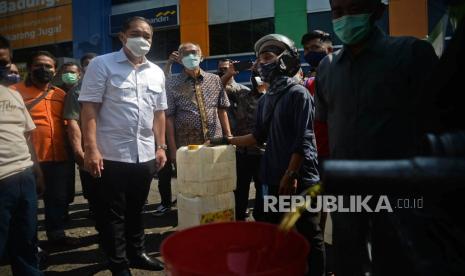 Menteri Perdagangan Muhammad Lutfi berbincang dengan warga yang mengantre membeli minyak goreng dengan harga Rp 10.500 per liter di pasar Kramat Jati, Jakarta, Kamis (3/3/2022). Dalam kesempatan tersebut Menteri Perdagangan juga meninjau harga dan ketersediaan kebutuhan bahan pokok dan minyak goreng. Prayogi/Republika.