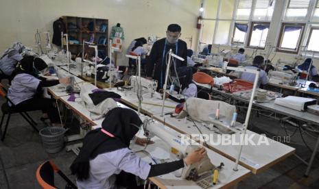 Sejumlah peserta mengikuti pelatihan keterampilan menjahit kain di Unit Pelaksanaan Teknis Dinas Balai Latihan Kerja (UPTD BLK) Kabupaten Garut, Jawa Barat, Kamis (24/9/2020). BLK Kabupaten Garut menerapkan protokol kesehatan seperti penggunaan masker, face shield, fasilitas cuci tangan, jaga jarak dan pengurangan kapasitas peserta hingga 50 persen guna menghindari risiko penyebaran pandemi COVID-19. 