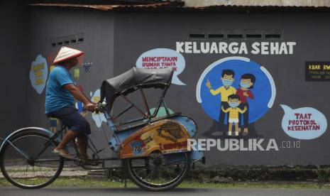 Warga melintas di depan mural edukasi kesehatan di kawasan Bibis, Banjarsari, Solo, Jawa Tengah, Selasa (6/4/2021). Mural yang berisi ajakan taat protokol kesehatan dan bebas asap rokok tersebut dibuat agar masyarakat lebih peduli terhadap kesehatan keluarga dan lingkungan pada masa pandemi COVID-19.