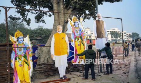 FILE - Para pekerja memasang gambar dewa Hindu Lord Ram dan Perdana Menteri India Narendra Modi untuk menandai pembukaan kuil besar Lord Ram di Ayodhya, India, Kamis, (18/1/2024).