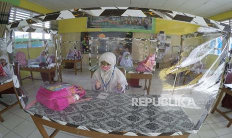 Sejumlah murid mengikuti kegiatan belajar secara tatap muka menggunakan meja bersekat plastik (ilustrasi). Pemkab Cianjur, Jawa Barat, membuka kembali sekolah yang berada di kecamatan dengan status zona hijau seiring penerapan adaptasi kebiasaan baru dengan menerapkan protokol kesehatan bagi guru dan siswa guna memutus rantai penyebaran COVID-19.