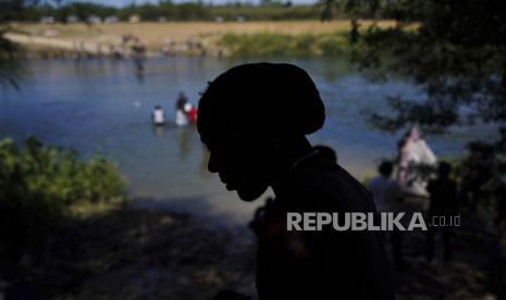 Seorang migran menunggu di sisi perbatasan Meksiko sebelum menyeberangi Rio Grande ke Del Rio, Texas, di Ciudad Acuna, Meksiko, Rabu, 22 September 2021.