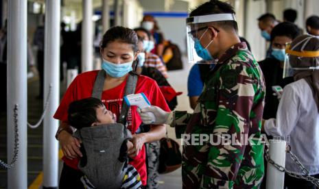 Petugas medis melakukan pemeriksaan suhu tubuh pekerja migran Indonesia (PMI) yang baru tiba di Pelabuhan Internasional Batam Centre, Batam, Kepulauan Riau, Kamis (21/5/2020). Sebanyak 293 PMI asal Malaysia dipulangkan melalui Batam dan akan dikarantina sementara hingga ada hasil pengecekan kesehatan untuk mencegah penyebaran COVID-19