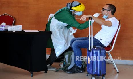 Penumpang pesawat menjalani tes Covid-19 berbasis PCR setibanya di Bandara Ngurah Rai, Bali.