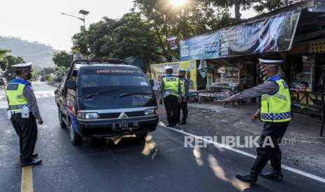 Petugas gabungan melakukan penyekatan kendaraan dengan plat nomor dari luar Garut di posko penyekatan larangan mudik di Jalan Nanggeleng, Limbangan, Kabupaten Garut, Ahad (9/5). Memasuki hari keempat penerapan larangan mudik Lebaran 2021, petugas gabungan di posko penyekatan larangan mudik Limbangan telah memutarbalikan sedikitnya 150 kendaraan berplat luar kota dari arah Bandung menuju Garut dan Tasikmalaya karena tidak memiliki surat kesehatan serta ijin perjalanan. Foto: Republika/Abdan Syakura