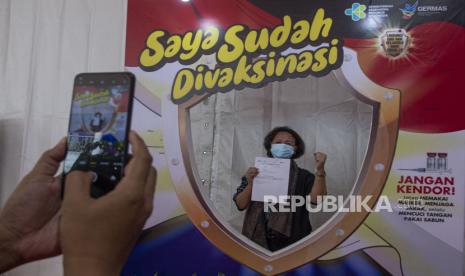 Seorang tenaga pendidikan berfoto usai menjalani vaksinasi COVID-19 dalam acara vaksinasi massal di SMA Negeri 70 Jakarta, Jakarta, Rabu (24/2/2021). Vaksinasi bagi pekerja publik dilakukan lewat pendaftaran secara kolektif di instansi masing-masing.