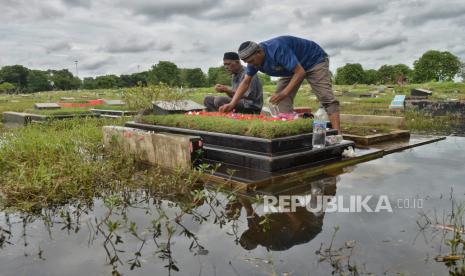 Warga melakukan ziarah kubur keluarganya di tempat pemakaman umum (TPU) yang terendam air di TPU Semper, Jakarta Utara, Ahad (3/3/2024). Tradisi ziarah kubur dilakukan umat Islam jelang bulan Ramadan yang akan jatuh sekitar sepekan ke depan. Kegiatan tersebut dilakukan untuk mendoakan keluarga yang sudah meninggal, sekaligus merawat makamnya meski dalam kondisi terendam.