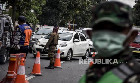 Petugas gabungan mengatur arus lalu lintas di pos pemeriksaan Pembatasan Sosial Berskala Besar (PSBB). Ilustrasi