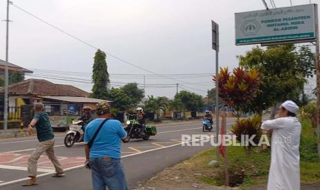 Sejumlah warga dan santri mencoba menghentikan rombongan moge Harley Davidson yang melintas di Jalan Nasional, Kecamatan Cihaurbeuti, Kabupaten Ciamis, Sabtu (27/5/2023). Seorang santri Pondok Pesantren Miftahul Huda Al Abidin diduga menjadi korban tabrak lari rombongan moge. 