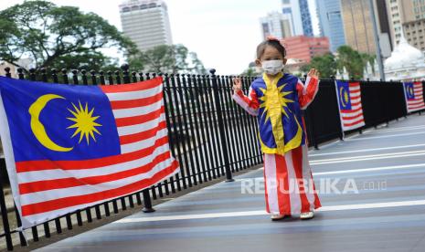 Seorang anak mengenakan pakaian Jalur Gemilang dengan memakai masker saat merayakan Hari Ulang Tahun (HUT) ke-64 Malaysia di Dataran Merdeka, Kuala Lumpur, Malaysia, Selasa (31/8/2021). Malaysia dan Singapura sudah melonggarkan aturan masker baru-baru ini. Ilustrasi.