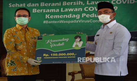 Wakil Menteri Perdagangan Jerry Sambuaga (kiri) secara simbolis menyerahkan donasi uang kepada Wakil Gubernur Banten Andika Hazrumi saat penyerahan bantuan Kemendag Peduli di Serang, Banten, Senin (18/5/2020). Untuk menangguangi penyebaran COVID-19 di Provinsi Banten, Kementerian Perdagangan menyerahkan sejumlah bantuan berupa uang tunai, APD serta bahan kebutuhan pokok