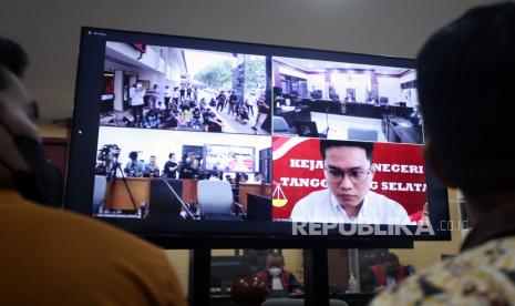 Terdakwa Indra Kesuma alias Indra Kenz (layar TV kanan) mendengarkan pembacaan vonis dalam kasus investasi bodong aplikasi Binomo secara hybrid di Pengadilan Negeri Tangerang, Tangerang, Banten, Senin (14/11/2022). Indra Kesuma alias Indra Kenz divonis sepuluh tahun penjara serta denda Lima Miliar Rupiah karena dinilai terbukti melakukan penyebaran informasi bohong soal investasi bodong Binary Option (Binomo) yang merugikan konsumen serta pencucian uang. 