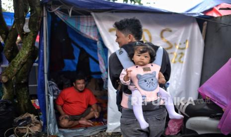 Warga korban gempa Cianjur beraktivitas di tenda pengungsian di Desa Cibulakan, Cuenang, Kabupaten Cianjur, Jawa Barat, Selasa (27/12/2022). Sebulan setelah terjadi gempa Cianjur pada 21 November 2022 lalu, sejumlah warga memilih bertahan di tenda pengungsian hingga mendapatkan bantuan dana stimulan perbaikan rumah dari pemerintah. Sementara pemerintah akan fokus membangun kembali hunian warga serta infrastruktur yang rusak dengan target rampung pada Junin2023 mendatang. 