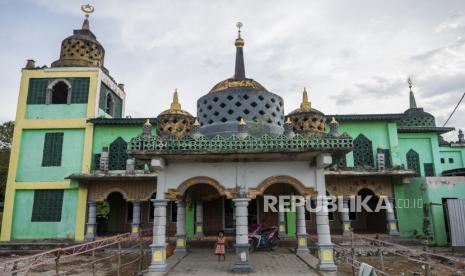 Seorang anak berdiri di depan Masjid Birr Aly yang kubahnya berarsitektur seperti stupa di Desa Bora, Sigi, Sulawesi Tengah, Selasa (12/4/2022). Meskipun mengalami kerusakan akibat gempa bermagnitudo 7,4 SR pada 2018 silam, namun masjid yang diilhami oleh bangunan candi dan dibangun oleh Hanafi Ali Ponulele pada 2015 dengan ukuran 12 meter x 12 meter, tinggi menara mencapai 15 meter itu tetap digunakan oleh umat Islam untuk beribadah. DMI Sigi Ajak Semua Pihak Makmurkan Masjid