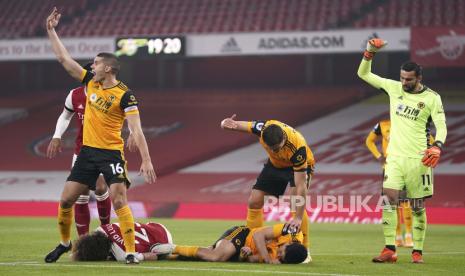 Para pemain memberi isyarat kepada staf medis setelah benturan kepala David Luiz dari Arsenal, kiri bawah, dan Raul Jimenez dari Wolverhampton Wanderers selama pertandingan sepak bola Liga Premier Inggris antara Arsenal dan Wolverhampton Wanderers di Emirates Stadium, London, Minggu, 29 November 2020.