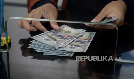 Karyawan menghitung mata uang dolar AS di gerai penukaran mata uang asing di Jakarta, Selasa (17/10/2023).