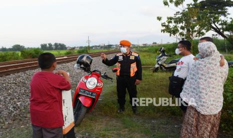 Seorang Polisi Khusus Kereta Api (Polsuska) memberikan sosialisasi pada warga di sekitar jalur Kereta Api (KA) saat melakukan pengawasan dan pengamanan jalur di Kota Madiun, Jawa Timur, Senin (19/4/2021). Kegiatan tersebut sebagai antisipasi agar aktivitas warga di jalur KA tidak membahayakan perjalanan KA, karena beberapa kali ditemukan keisengan warga menaruh batu di atas rel. 