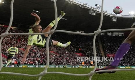 Pemain  Manchester City Erling Haaland (tengah) mencetak gol ketiga timnya melewati kiper Southampton Gavin Bazunu pada pertandingan sepak bola Liga Premier Inggris antara Southampton dan Manchester City di Stadion St Mary di Southampton, Inggris, Ahad (9/4/2023) dini hari WIB.