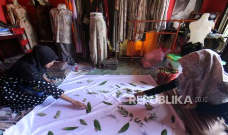 Pekerja membuat pola dari daun diatas kain di rumah produsen kain ecoprint Usaha Mikro Kecil Menengah (UMKM) Ija Lhee Sagoe (ILS) di Desa Kuta Blang, Lhokseumawe, Aceh, Senin (9/1/2023). 