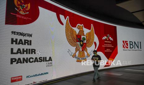 Seorang pria melintas di depan layar LED yang bertuliskan Peringatan Hari Lahir Pancasila di Menara BNI, Jakarta, Senin (1/6/2020). BNI turut serta memperingati Hari Lahir Pancasila yang jatuh setiap tanggal 1 Juni setiap tahunnya