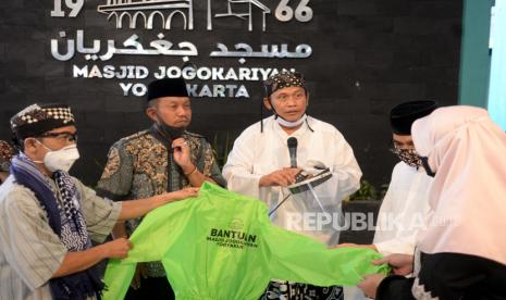 Ketua Dewan Syuro Takmir Masjid Jogokariyan, Ustaz Muhammad Jazir  (kedua kanan) bersama Walikota Jogja haryadi Suyuti (kedua kiri) saat penyerahan bantuan baju APD di Masjid Jogokariyan, Yogyakarta, Jumat (24/4). Sebanyak 300 baju APD dari Masjid Jogokariyan disalurkan kepada tenaga medis, TNI, Polisi, dan media