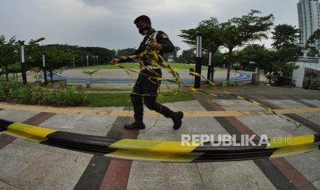 Petugas Pengamanan Dalam (Pamdal) Kompleks Gedung Sate memasangkan pita pembatas di area trotoar Lapang Gasibu Bandung, Kamis (20/5). Setahun terakhir salah satu landmark kota Bandung ini ditutup untuk umum akibat pandemi.