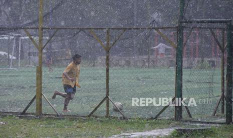 Sejumlah anak bermain bola saat hujan.  BMKG memprakirakan hujan akan mengguyur sejumlah kota besar di Indonesia