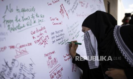 Seorang pengunjuk rasa menulis pesan saat melakukan protes di Konsulat Amerika Serikat sebagai bagian dari hari aksi global mendukung kemerdekaan Palestina, di Johannesburg, Afrika Selatan, (13/1/2024