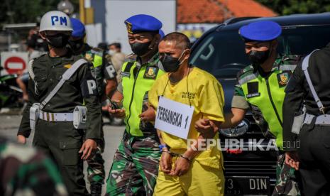 Petugas membawa tersangka dengan inisial P saat rekonstruksi kecelakaan tabrak lari di Jalan Nasional III, Desa Ciaro, Nagreg, Kabupaten Bandung, Jawa Barat, Senin (3/1/2022). Polisi Militer Angkatan Darat melakukan sejumlah adegan dalam rekonstruksi kecelakaan tabrak lari yang menewaskan dua orang korban dengan tiga orang tersangka anggota TNI AD.  