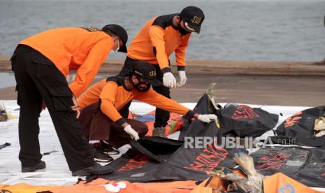 Anggota Badan Pencarian dan Penyelamatan Nasional (BASARNAS) memeriksa puing-puing pesawat Sriwijaya Air penerbangan SJ 182, yang ditemukan dari lokasi kecelakaan di perairan Jakarta, di pelabuhan Tanjung Priok di Jakarta, Indonesia, 19 Januari 2021. Penerbangan Sriwijaya Air SJ182 jatuh ke laut lepas pantai Jakarta pada tanggal 09 Januari 2021 sesaat setelah lepas landas dari Bandara Internasional Jakarta dalam perjalanan ke Pontianak di provinsi Kalimantan Barat.