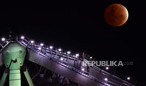  Bulan terlihat di atas Jembatan Story Brisbane saat bayangan bumi menutupi bulan selama gerhana bulan parsial di atas Brisbane, Australia, 19 November 2021. Badan Meteorologi Klimatologi dan Geofisika (BMKG) menyebutkan fase gerhana bulan total akan berlangsung selama tujuh jam. 