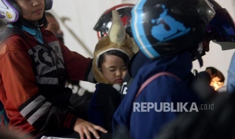 Pemudik sepeda motor yang membawa anaknya mengantri memasuki kapal di Pelabuhan Merak ,Banten, Selasa (12/6) dini hari.