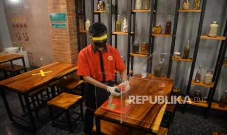 Pegawai dengan menggunakan face shield menata meja yang dipasang sekat akrilik di restoran Bebek Kaleyo, Cempaka Putih, Jakarta, Kamis (4/6). Sejumlah restoran mulai bersiap menghadapi tatanan hidup normal baru (new normal) dengan menerapakan protokol kesehatan yang ketat seperti menggunakan pelindung wajah, masker, sarung tangan bagi karyawan, menjaga jarak dan pemeriksaan suhu tubuh bagi  konsumen sebagai standar operasional prosedur (SOP) dalam mencegah penyebaran Covid-19