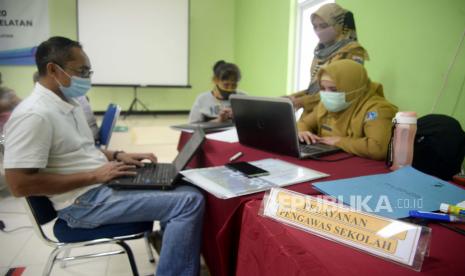 Petugas membatu orang tua murid di posko pelayanan Penerimaan Peserta Didik Baru (PPDB) di SMA Negeri 70, Jakarta, Selasa (16/6). Orang tua murid di Jakarta akan melakukan aksi massa guna menolak petunjuk teknis (Juknis) penerimaan sekolah berdasarkan zonasi yang mengacu pada usia siswa.