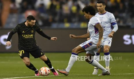 Pemain PSG Lionel Messi membawa bola dibayangi Pemain Riyadh XI Luiz Gustavo (tengah) dan Cristiano Ronaldo (kanan) saat pertandingan sepak bola persahabatan, di Stadion Universitas King Saud, di Riyadh, Arab Saudi, Jumat, (20/1/2023)dini hari. 