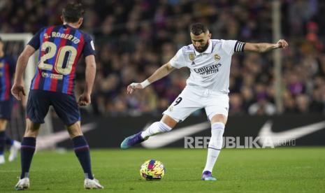 Pemain Real Madrid Karim Benzema (kanan) menendang bola melewati pemain Barcelona Sergi Roberto pada pertandingan sepak bola La Liga Spanyol antara Barcelona dan Real Madrid di stadion Camp Nou di Barcelona, ??Spanyol, Senin (20/3/2023) dini hari WIB. 